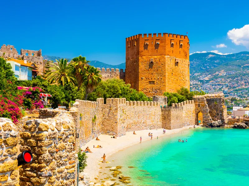 The Red Tower and castle walls above a small beach at Alanya