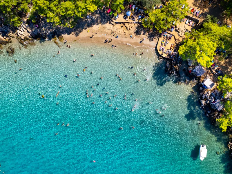 A small turquoise cove with swimmers, seen from directly overhead