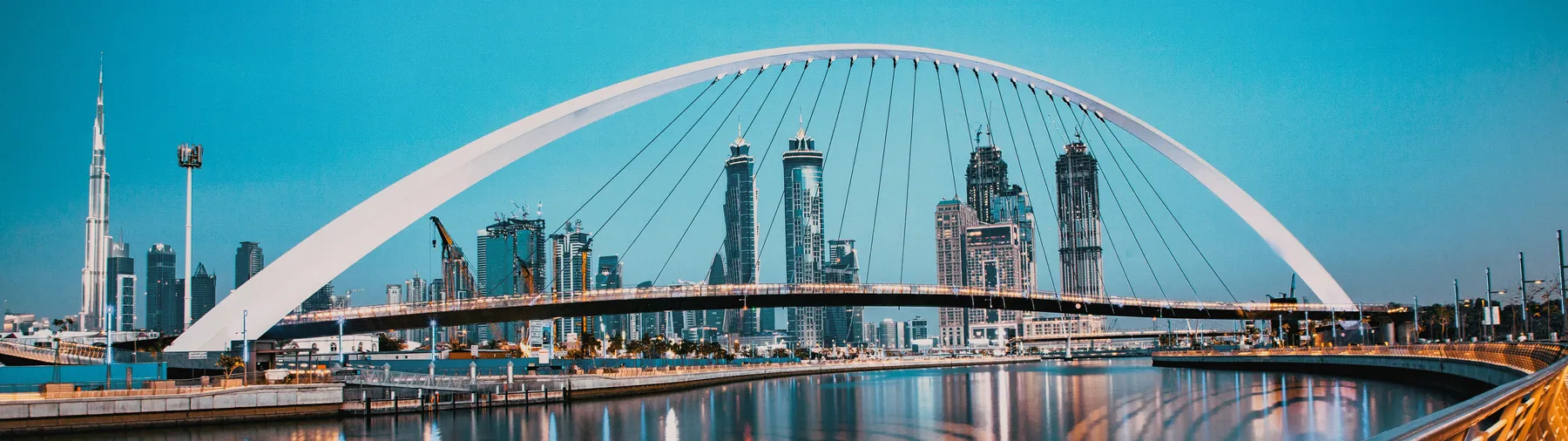 The Tolerance Bridge arching over Dubai Water Canal with towers behind