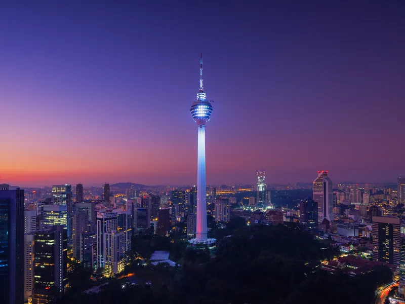 The KL Tower lit at dusk above the city rooftops