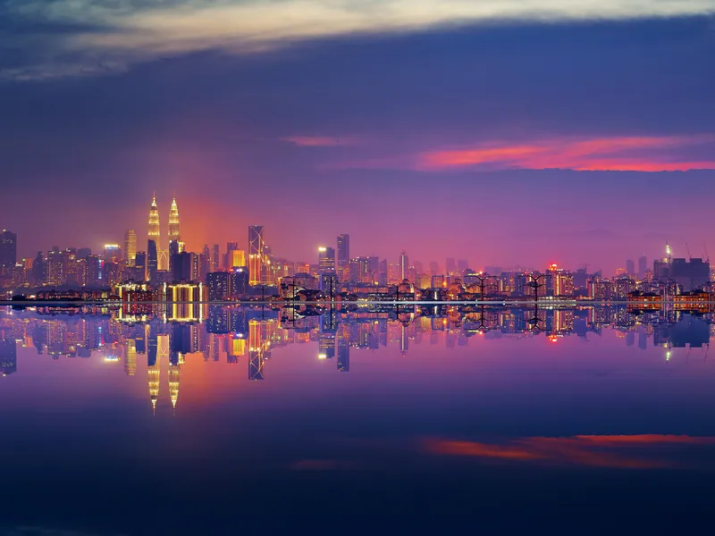 The Kuala Lumpur skyline reflected in still water at dusk