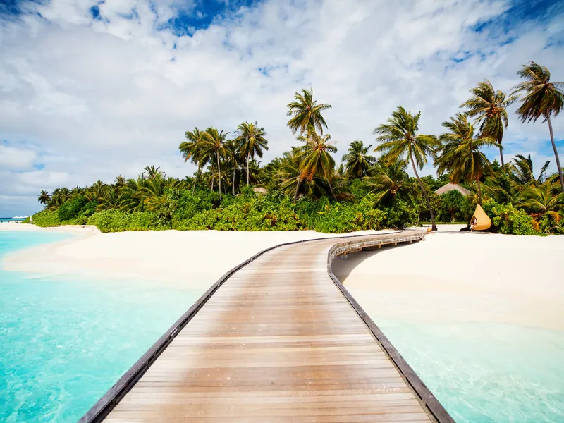 A wooden walkway leading to overwater villas above clear water