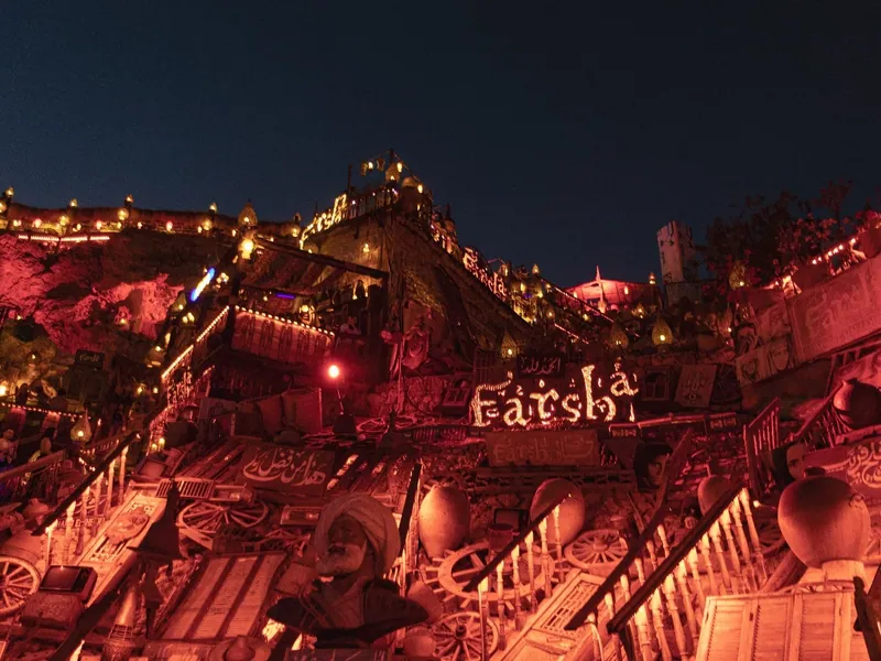 A terraced cliffside cafe lit with lanterns at night