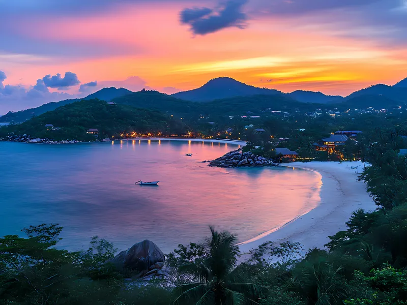 A curved bay on Koh Samui at sunset with hills behind