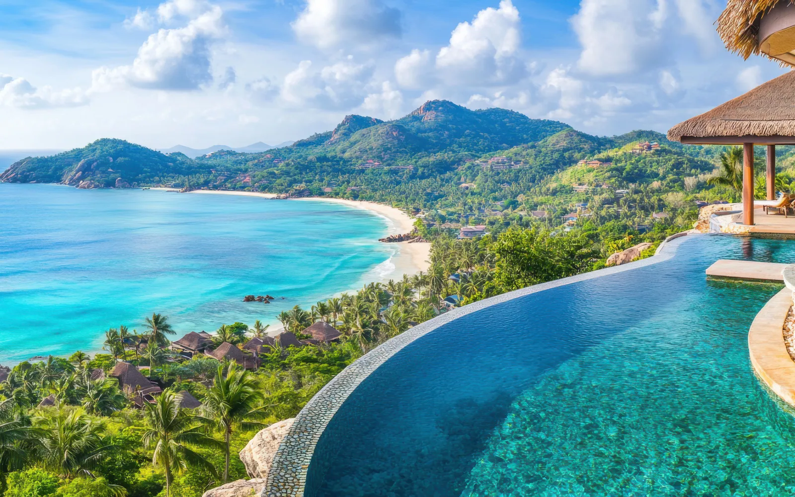 An infinity pool overlooking a palm-fringed bay on Koh Samui