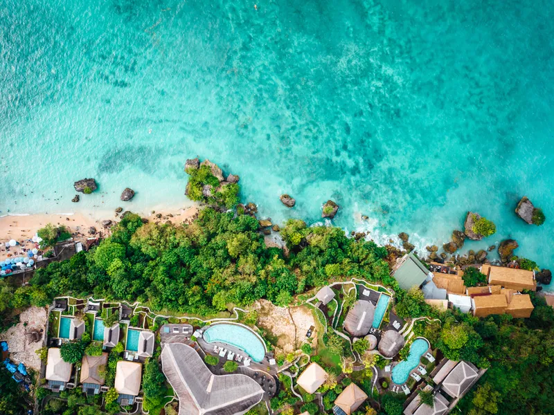An aerial view of a turquoise bay with resorts along the shore