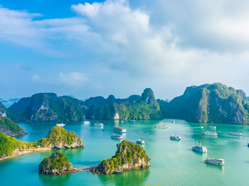 Karst islands and boats in the still water of Ha Long Bay